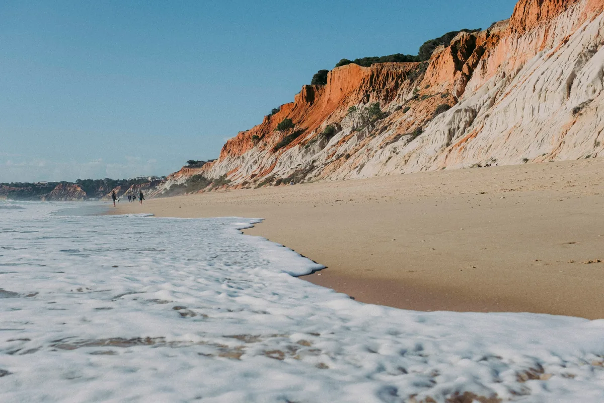Red and white cliffs above the long sands of Praia da Falésia