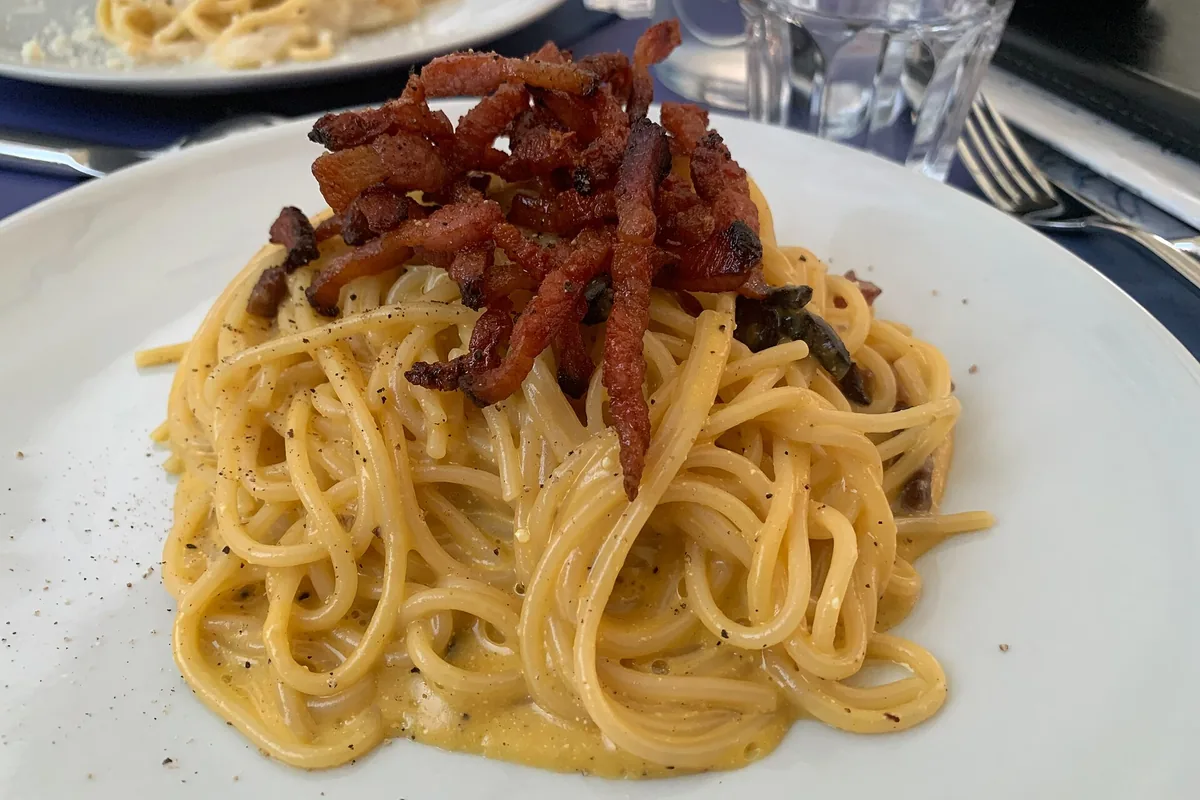 Spaghetti carbonara topped with crisp guanciale in Trastevere, Rome