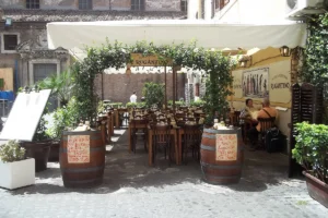 Outdoor tables under a vine-covered pergola at Antica Osteria Rugantino, a trattoria in Trastevere, Rome