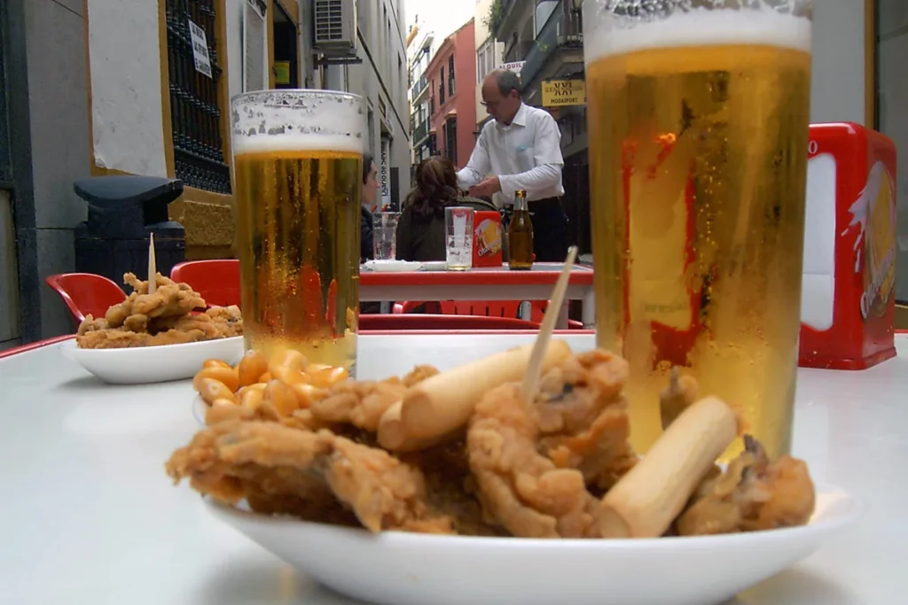 Beer and a plate of fried fish tapas on a bar counter in a Seville street