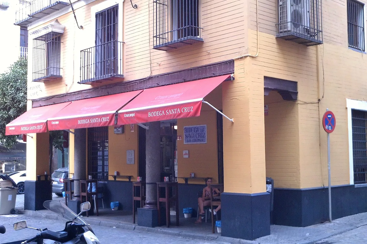 The corner exterior of Bodega Santa Cruz Las Columnas, with its red awning, in Seville