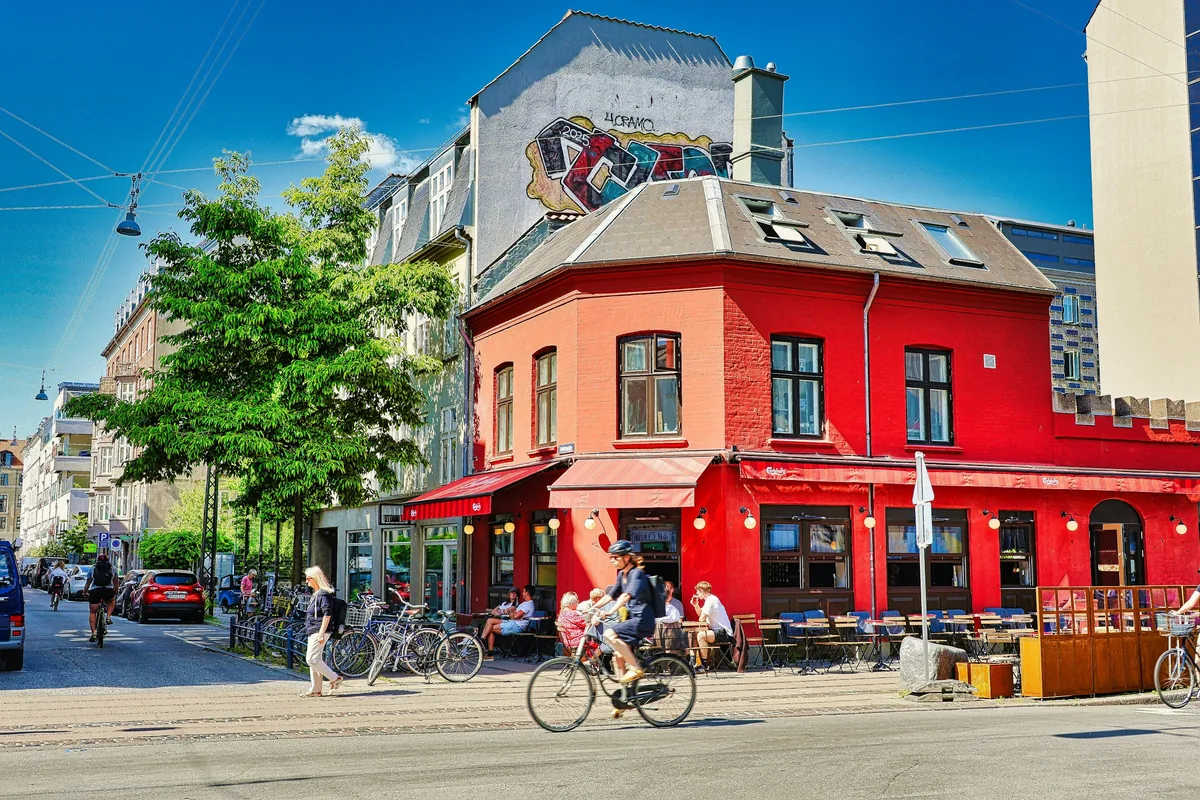 A red corner cafe with pavement tables on a sunny street in Copenhagen