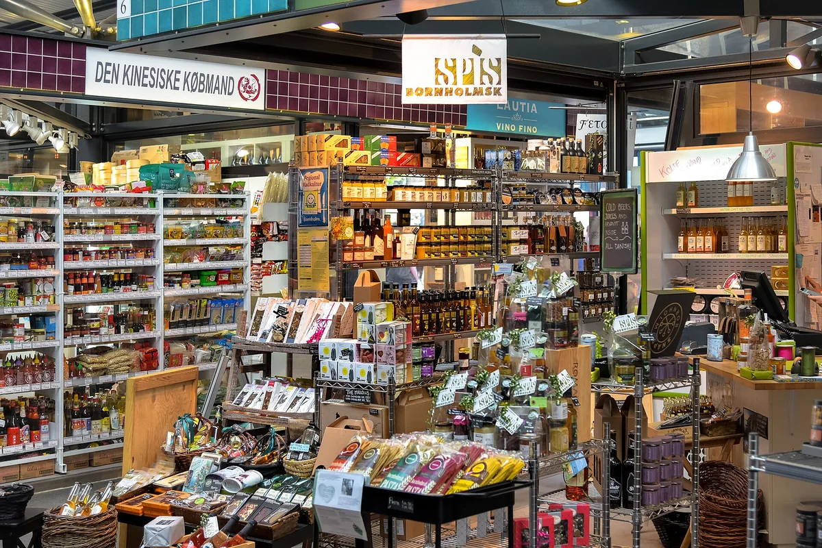 Shelves of groceries and deli stalls inside the glass market halls of Torvehallerne in Copenhagen