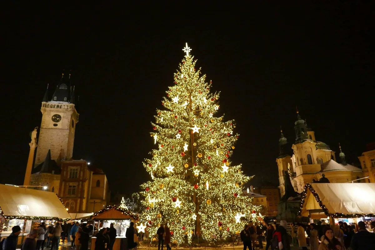 Giant Christmas tree and market stalls on Prague's Old Town Square at night