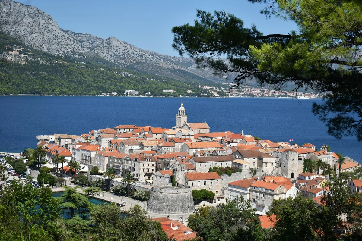 Walled old town of Korčula on its peninsula with mountains across the channel