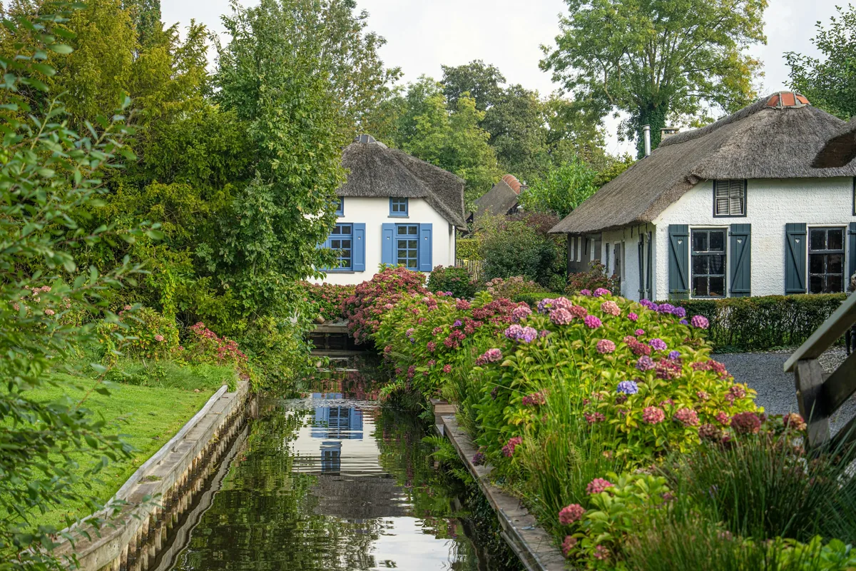Thatched cottages beside a flower-lined canal in Giethoorn, the Netherlands