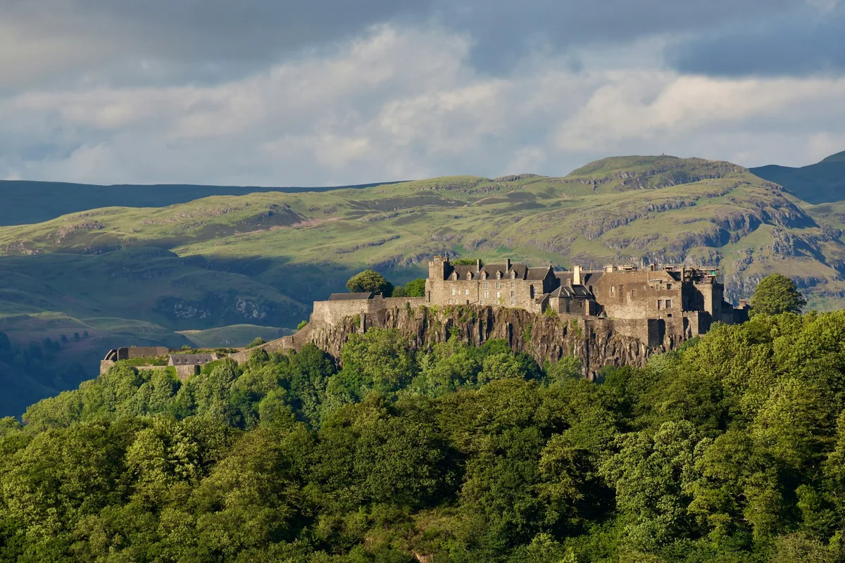 Stirling Castle on its rocky crag above wooded slopes, with hills behind