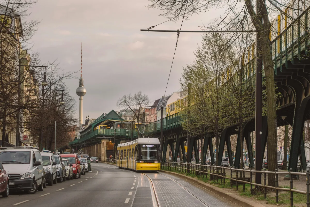 Elevated U-Bahn tracks above a street in Berlin, with the TV Tower in the distance