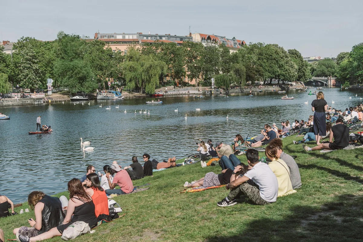 The Landwehr Canal in Berlin, with people sitting on the grassy bank