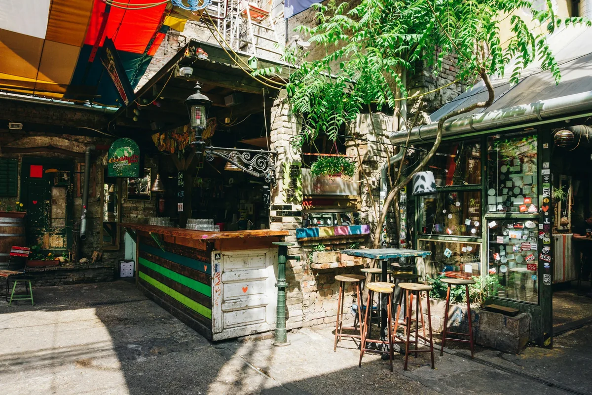 Tables and stools in the Szimpla Kert ruin bar courtyard next to Karaván in the Jewish Quarter, Budapest