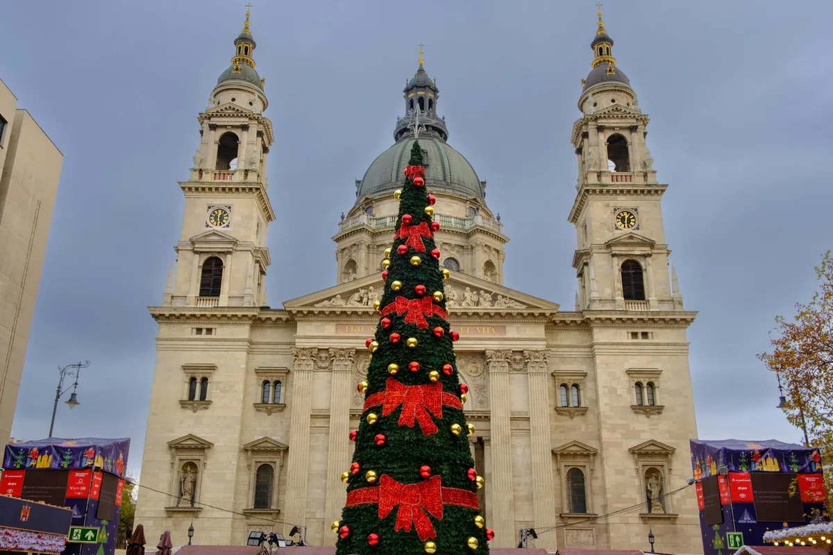 St Stephen's Basilica in Budapest with a Christmas tree and market stalls in front at dusk