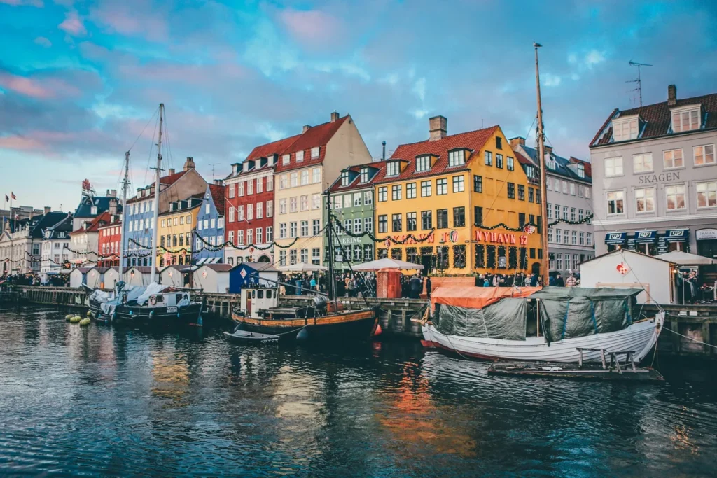 Boats moored along the Nyhavn canal in front of colourful townhouses in Copenhagen