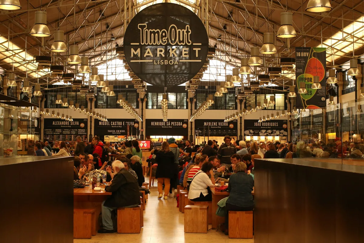 Diners at long communal tables inside Time Out Market in Lisbon