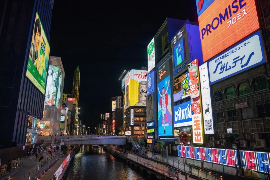 Neon signs and food stalls along the Dotonbori canal in Osaka, Japan