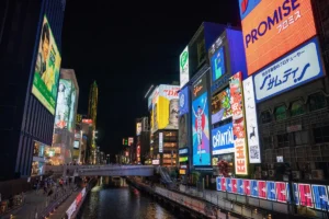 Neon signs and food stalls along the Dotonbori canal in Osaka, Japan