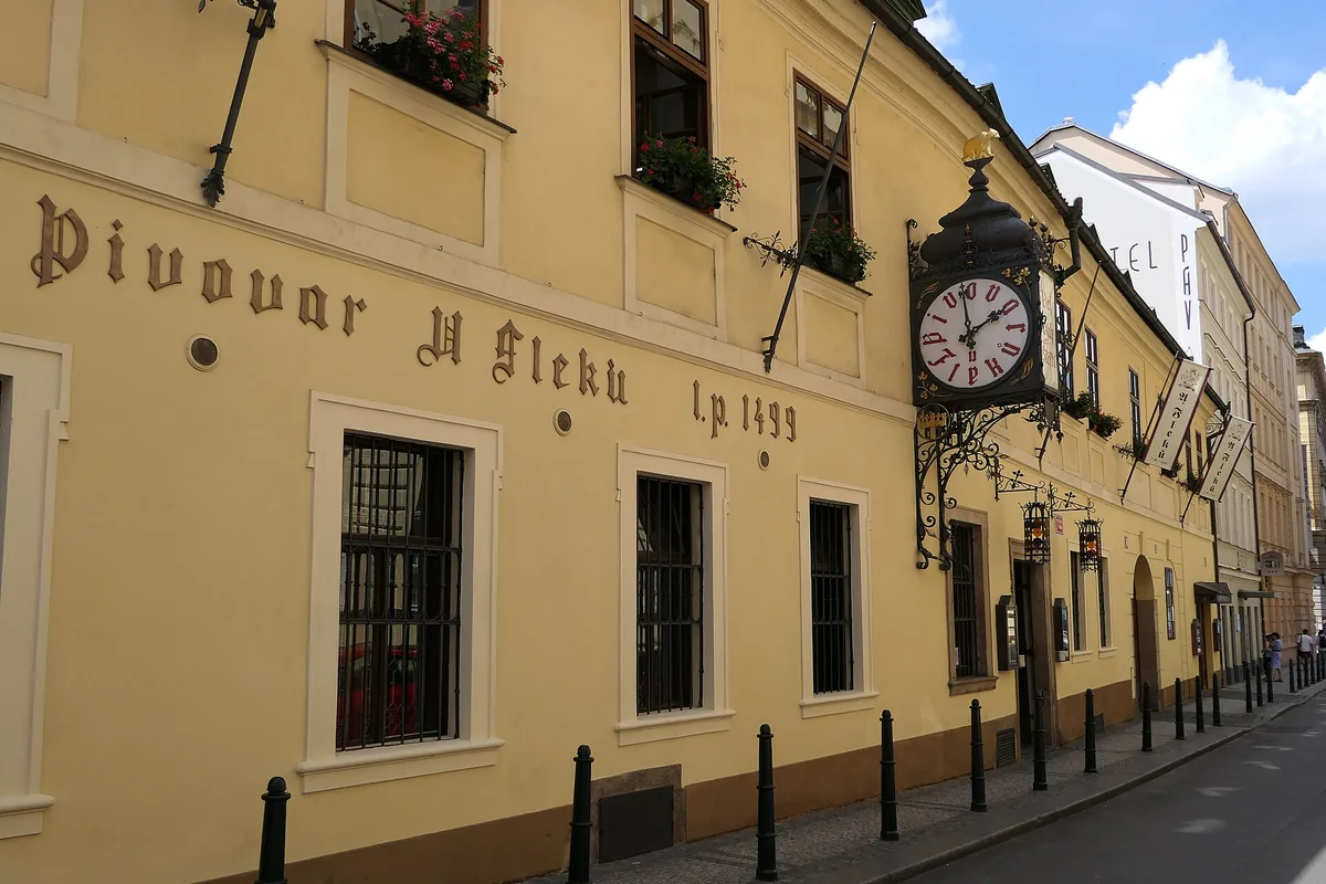 The yellow facade of the U Fleků brewery pub on Křemencova street in Prague's New Town, with its painted name and large hanging clock