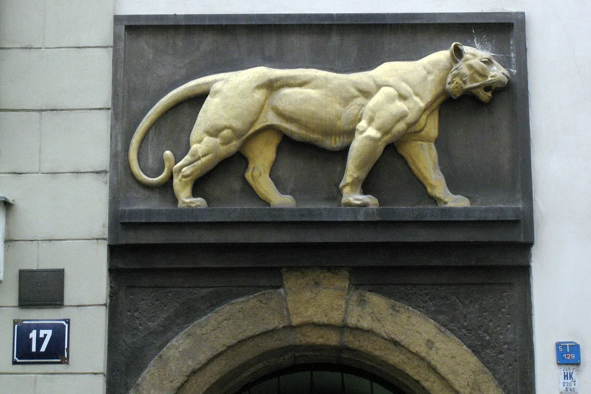 The gilded tiger house sign above the arched entrance of U Zlatého tygra at Husova 17 in Prague's Old Town