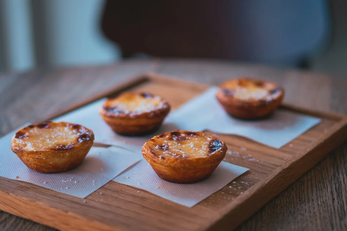 Four Portuguese custard tarts, pastéis de nata, on a wooden board