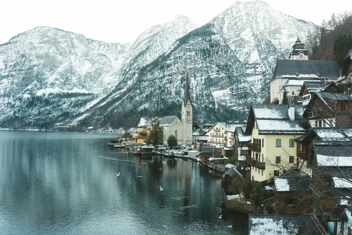 Hallstatt's lakeside houses and church below snowy mountains in winter